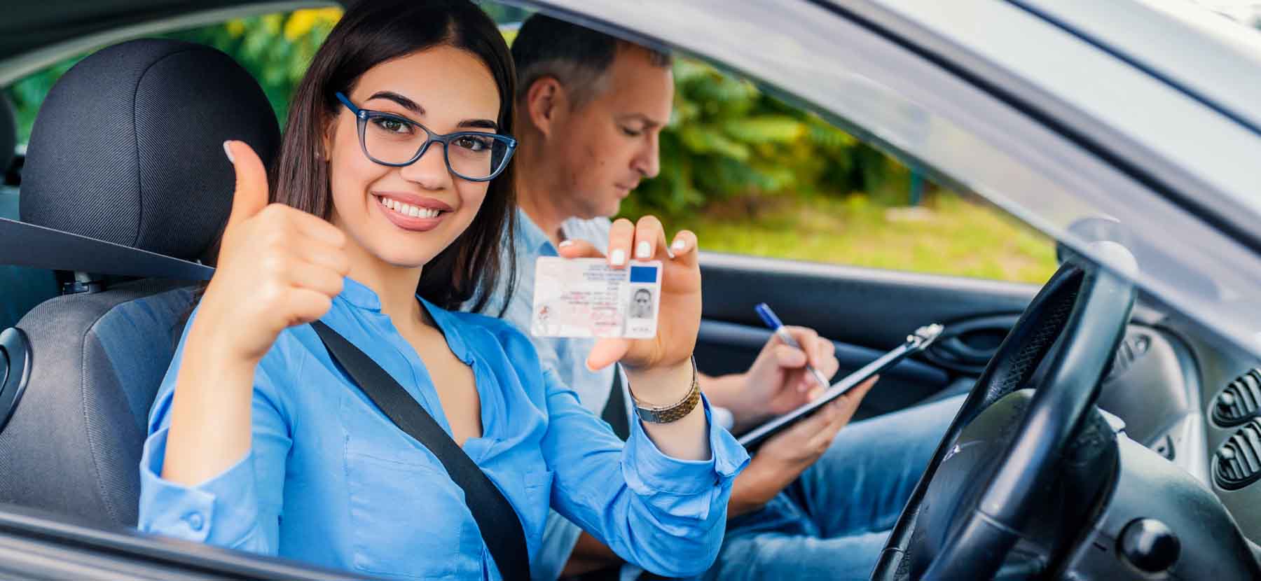 student showing driving license sitting besides her instructor in driving school Irving